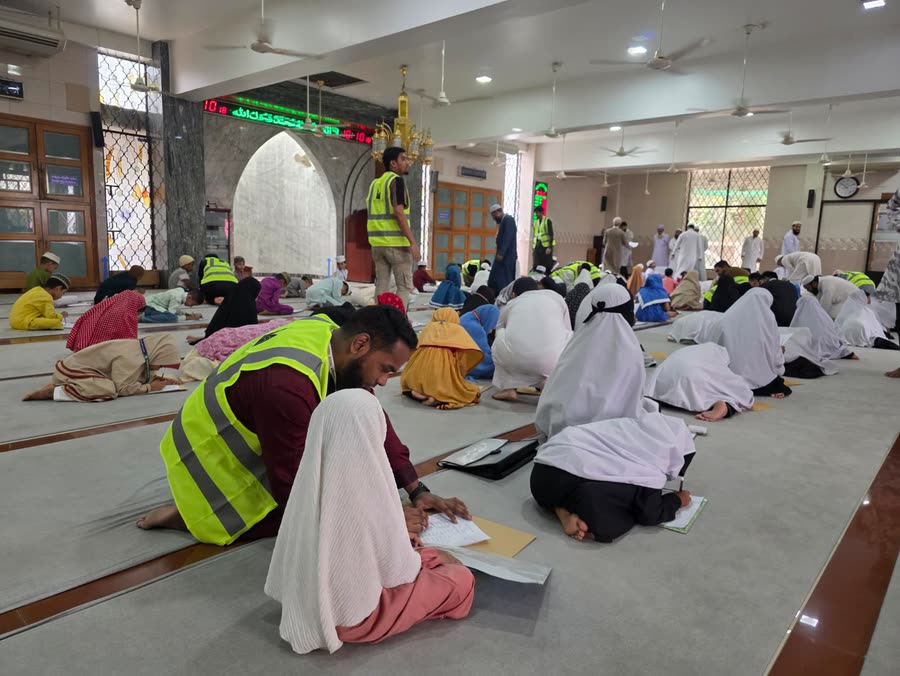 একজন স্বেচ্ছাসেবক এক শিশুকে খাতা লিখতে সহায়তা করছেন